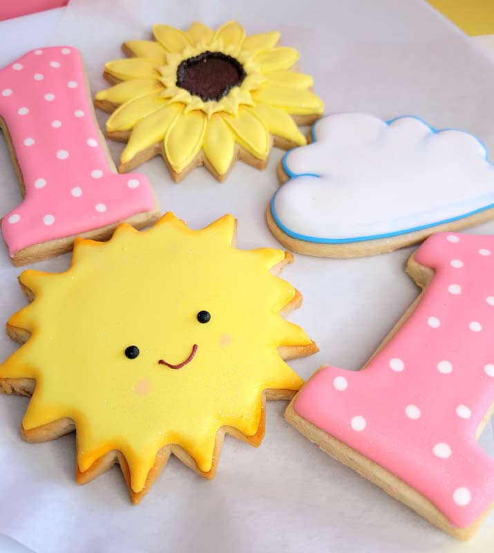 first firthday floded cookies - smiling sun, whte cloudm sunflower and pink and white polka-dotted number 1