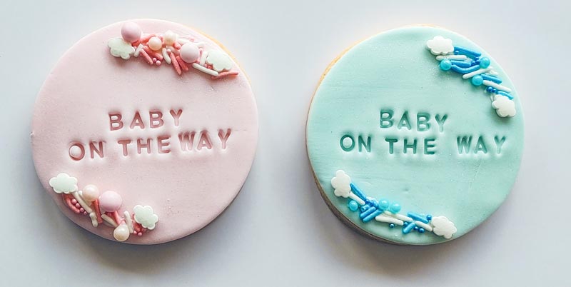 Fondant covered sugar cookies with "baby on the way" stamped on them