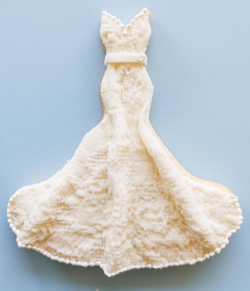 wedding gown shaped sugar cookie with fondant decoration giving a 3-d effect