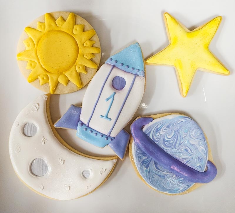 flooded sugar cookies in sun, moon, star and shape ship shapes for a baby's first birthday