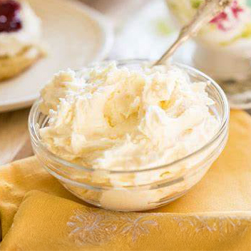 small bowl of English Clotted Cream with a silver teaspoon set on a folded napkin